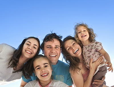 Family smiling with a blue sky background