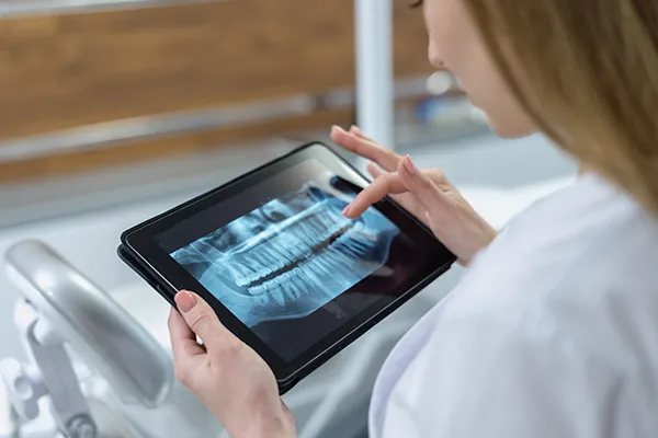 White dentist reviews a patient's digital xrays on her tablet device
